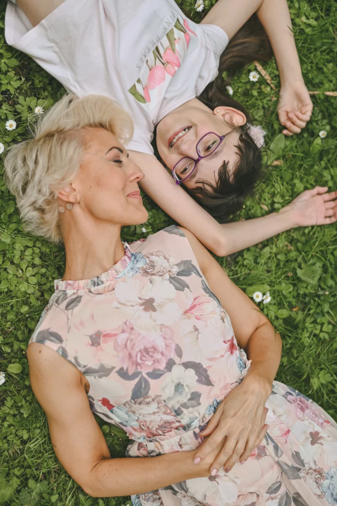 mama z córką patrzą na siebie leżąc na trawie